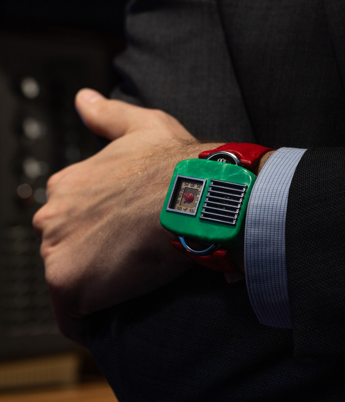 Green futuristic watch with red strap, seen on wrist