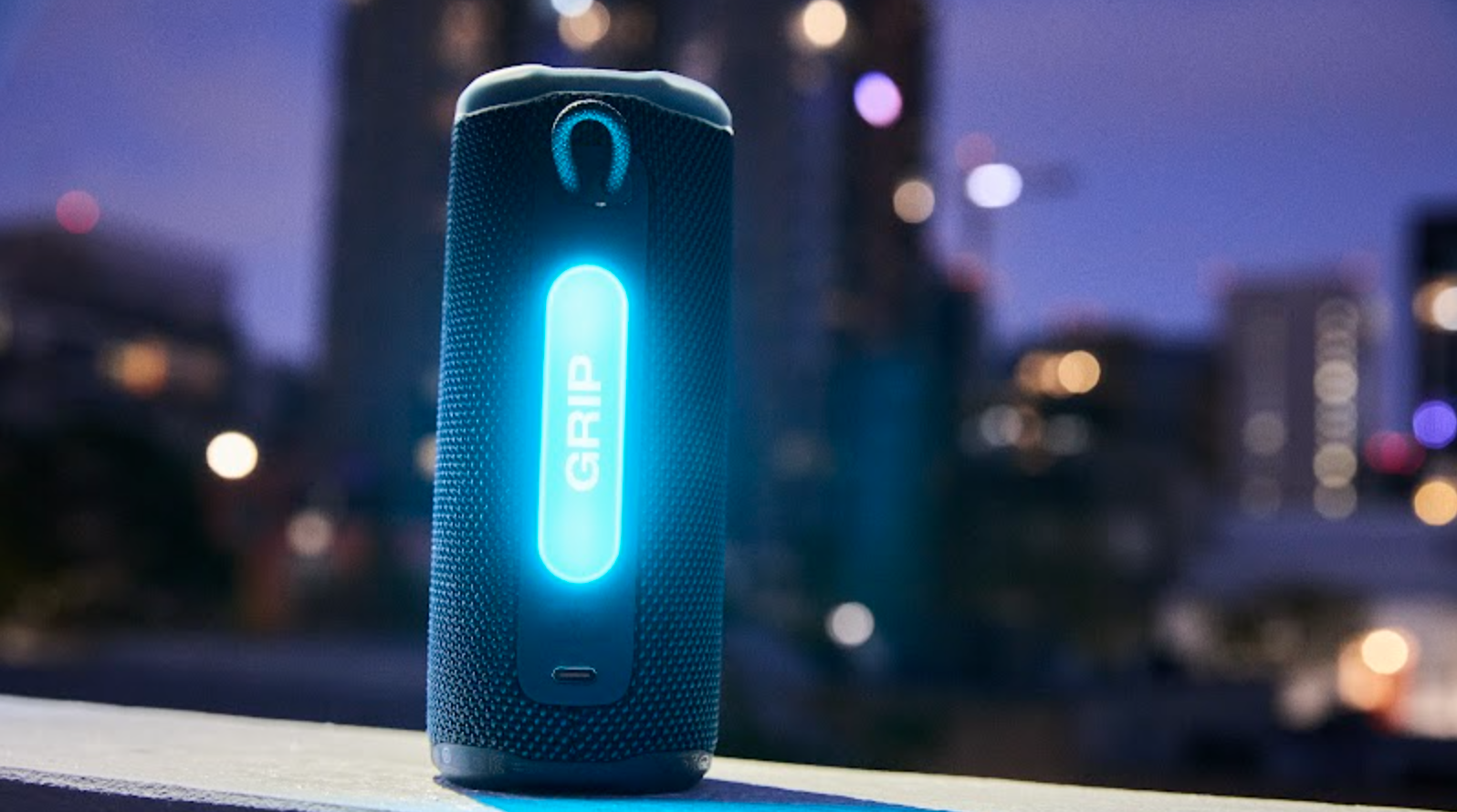 JBL Grip in front of a skyline, showing its illuminated ambient light panel