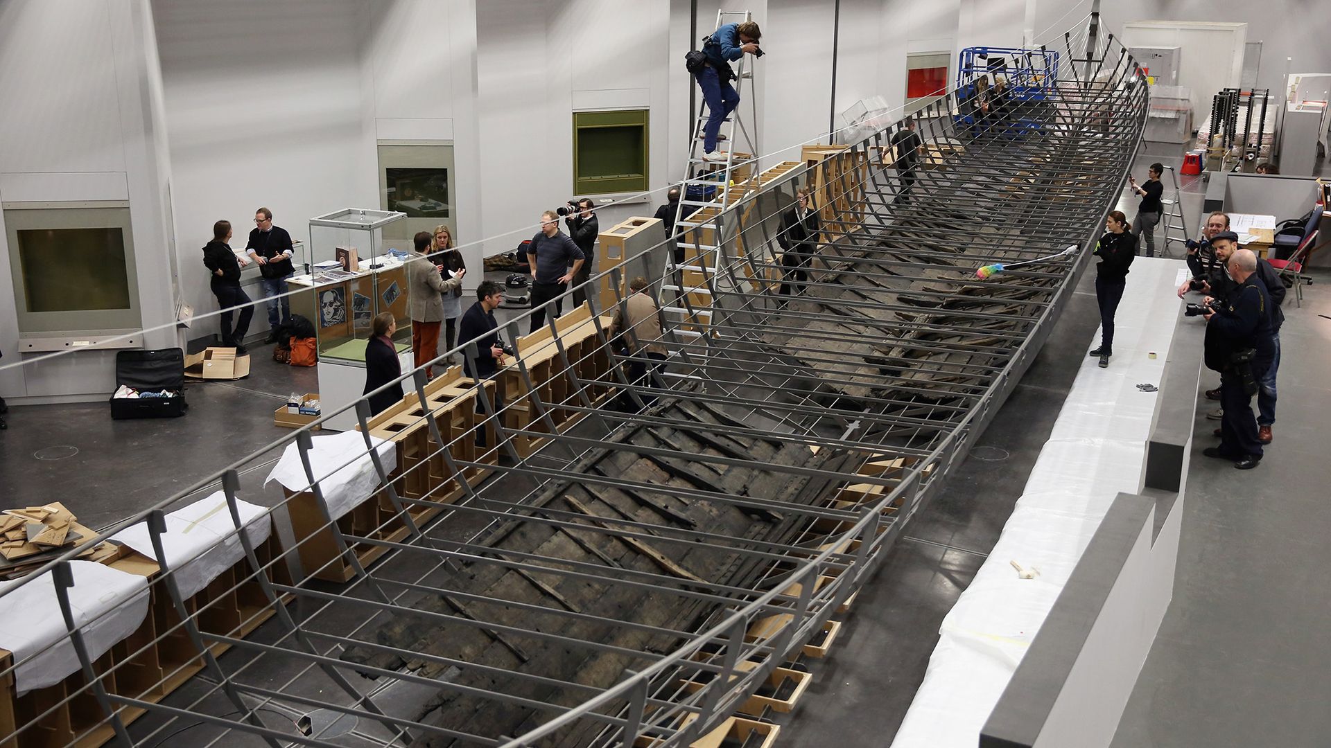 A group of workers build a large wooden boat.