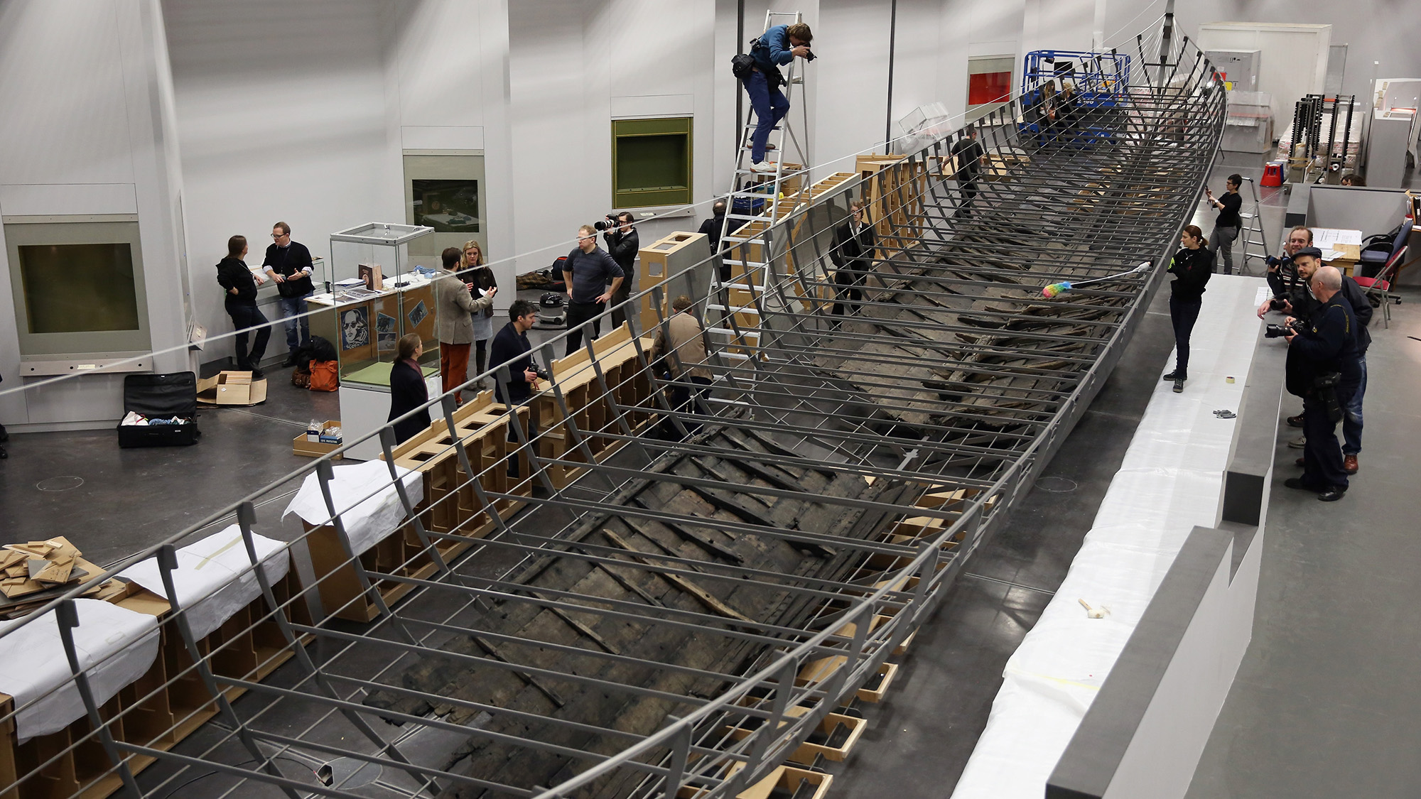 A group of workers build a large wooden boat.