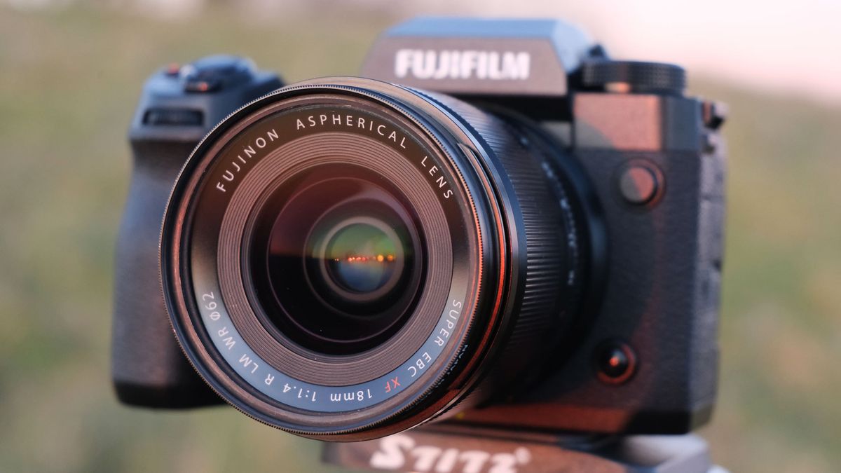 The Fujifilm X-H2 with the Fujifilm XF 18mm f/1.4 lens attached and a field in the background