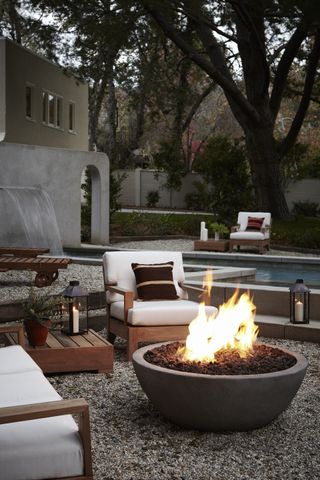 firepit on patio surrounded by garden armchairs
