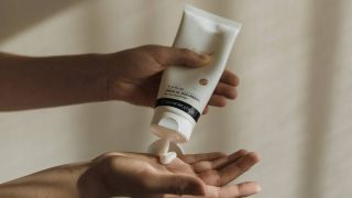 Woman squeezing moisturiser out of a tube into her hand