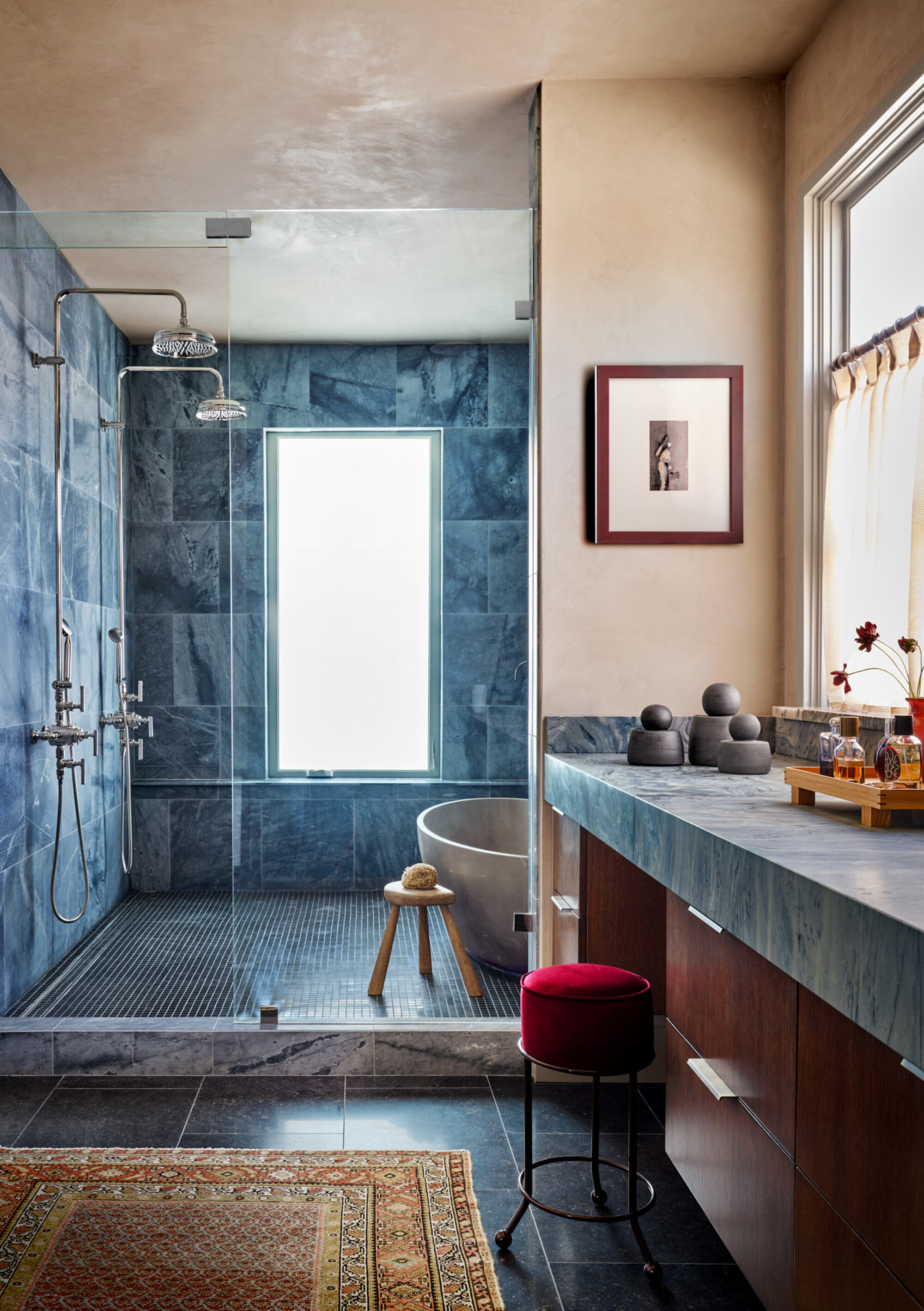 modern wet room bathroom with plaster walls, tiled shower, persian rug, vanity with stool, and cafe curtains over window