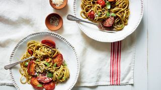 Two bowls of balsamic tomato pasta on a cloth with pots of seasoning on the side