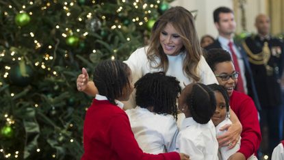 US First Lady Melania Trump hugs children in the East Room as she tours Christmas decorations at the White House in DC