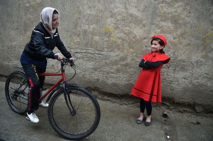 Afghan cyclist Kobra Samim talks with a young girl by a roadside in Kabul