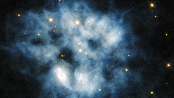 The cool, dim star at the center of the blue haze cloud is a white dwarf. The planetary nebula NGC 2452 is located in the southern constellation of Puppis.