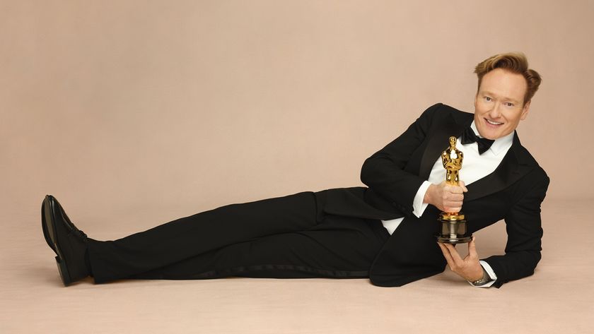 Conan O&#039;Brien lies down in a black tuxedo holding a golden Oscar trophy ahead of his first time gig hosting the Oscars at the Dolby Theatre.