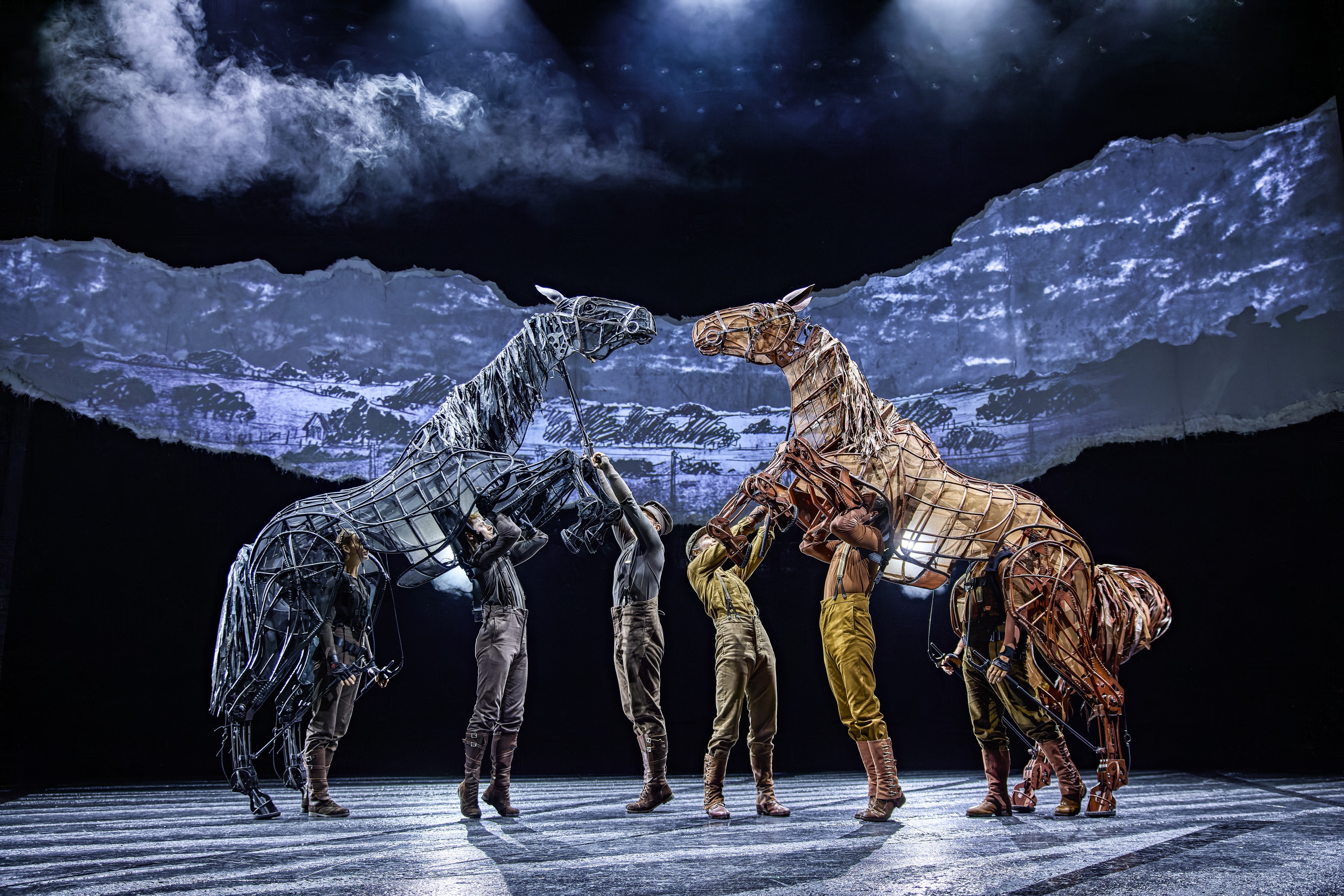 Two life-sized horse puppets rise up to one another on stage during War Horse performance