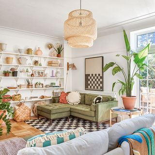Open-plan living room with open shelving along one wall and a green corner sofa