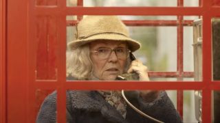 Julie Walters gazes at something suspicious while using a phone booth in Paddington 2.