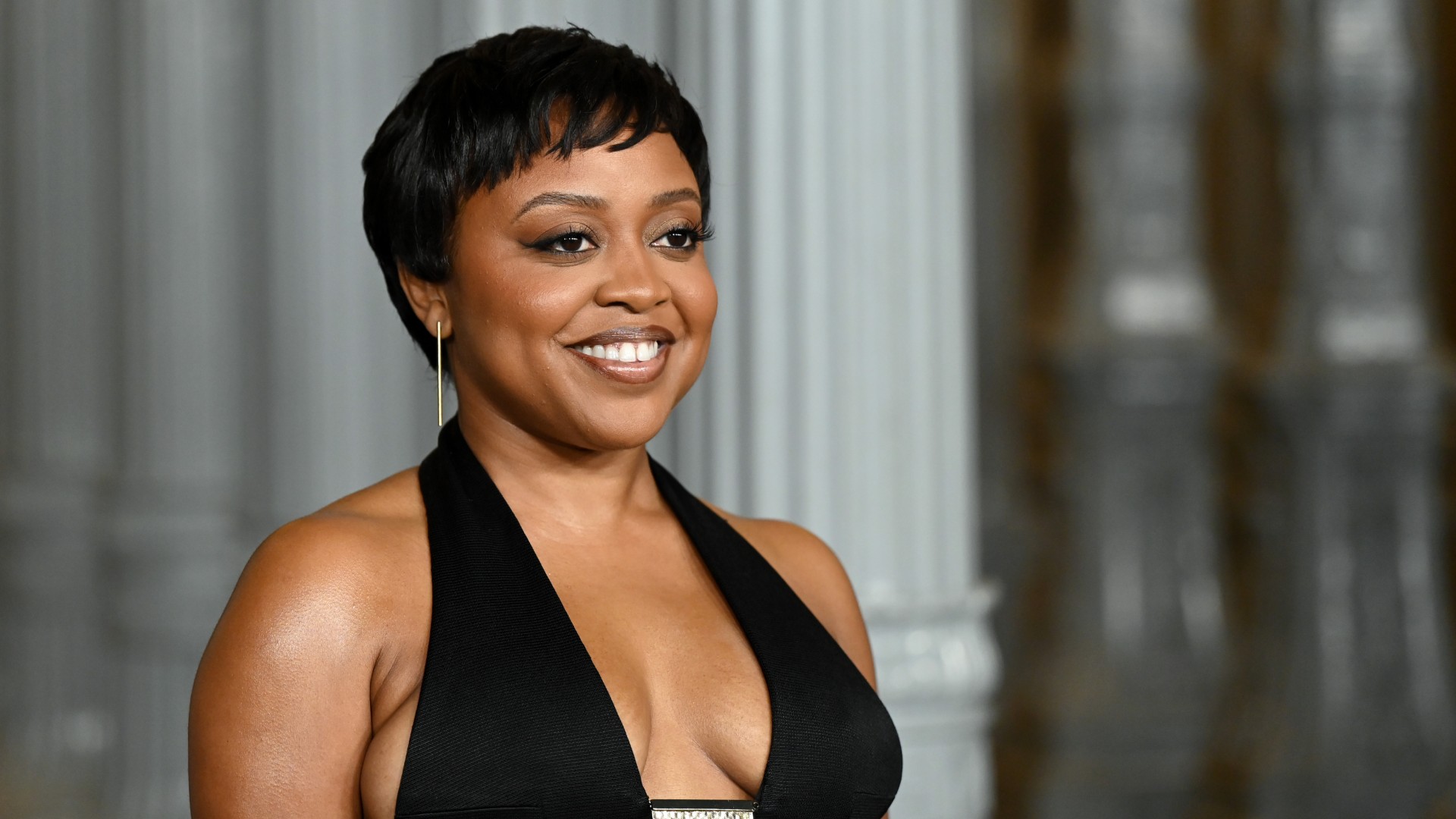 a black woman with short hair posing for paparazzi at a red carpet event