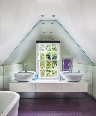 Child's bathroom with pitched ceiling, mirror glass walls, a vanity unit with twin basins and purple flooring
