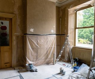 living room with wall panelling covered in plastic sheets while room is decorated