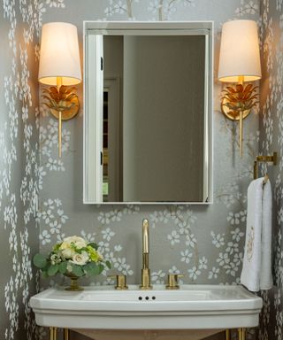 Powder room with wallpaper, two lamp shades, mirror, sink