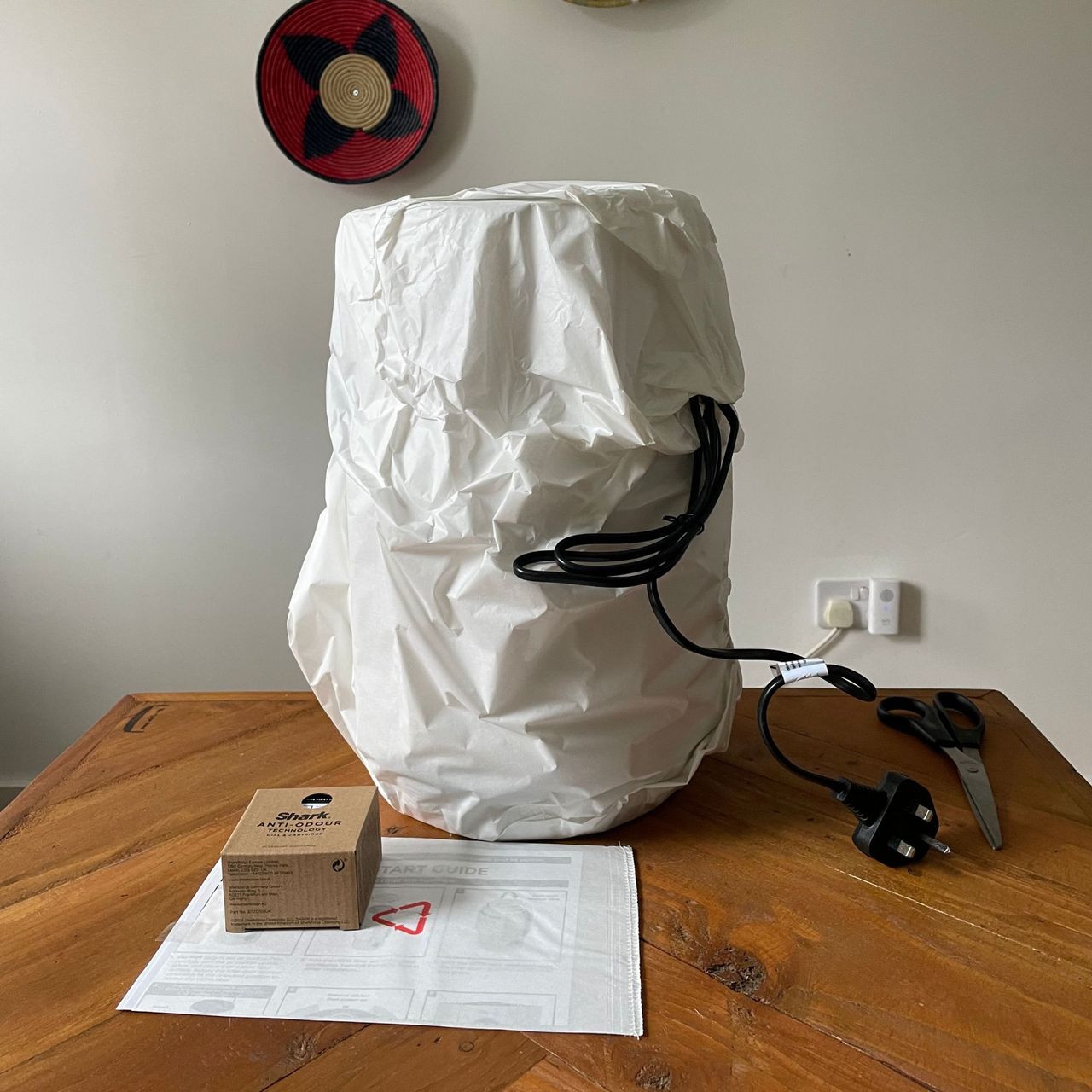 Shark NeverChange 5 Air Purifier wrapped in paper packaging sitting on a wooden table