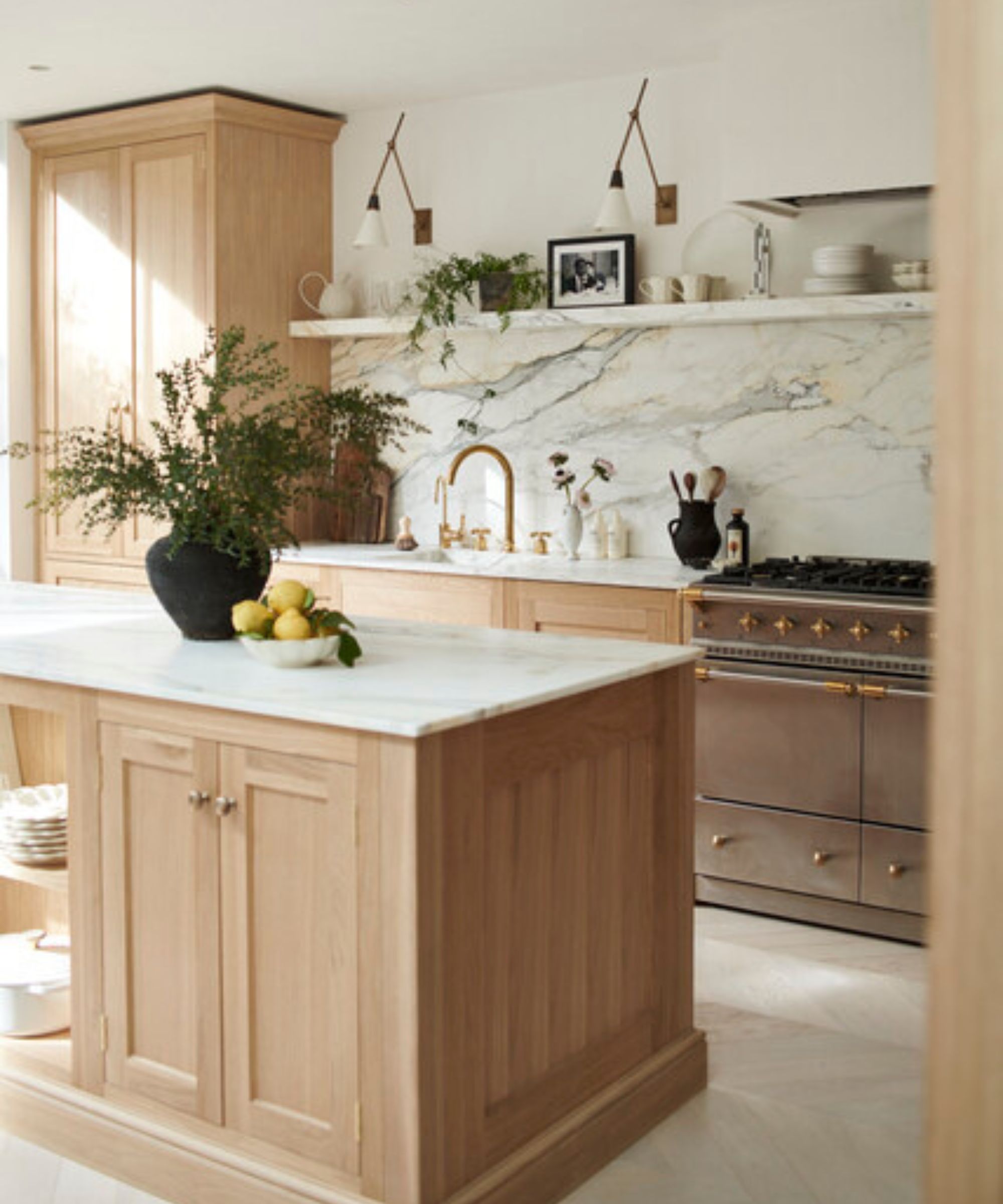 A light wood sociable kitchen with marble countertops, a large island, and counter seating