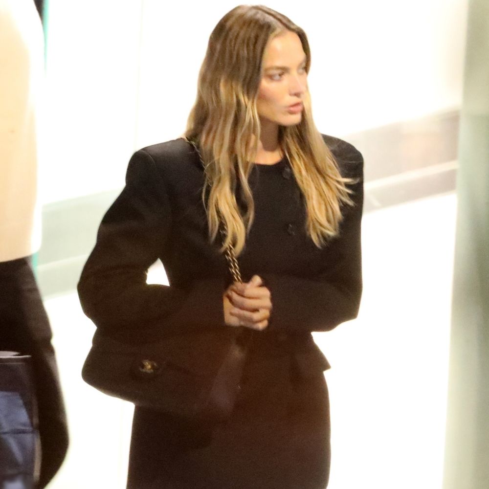 Margot Robie walks down the street wearing the black Wardrobe.NYC blazer dress with a Chanel classic flap bag and black wedge heels.