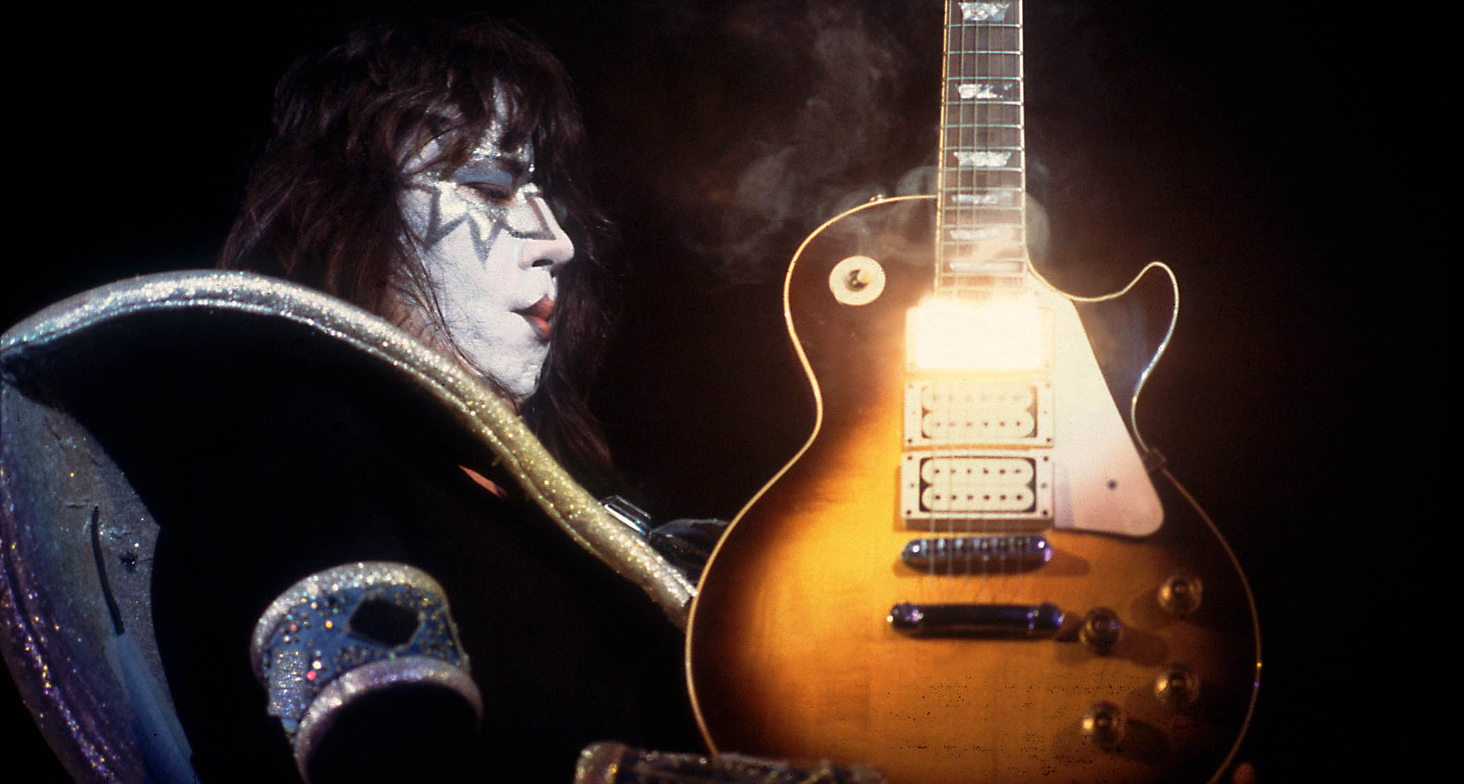 Ace Frehley holds a smoking hot Les Paul, with heat and light emitting from that neck humbucker position