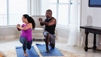 Woman and man holding a lunge and twist while working out at home