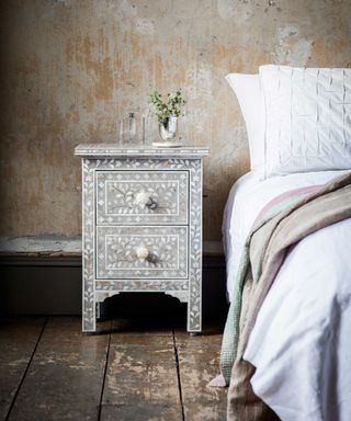 bedside table with pearl patterned accents and a double bed