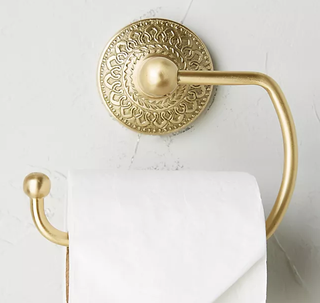 A brushed brass toilet roll holder