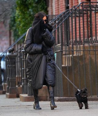 A photo of Irina Shayk matching her hefty black sleeping bag coat to that of her dog—a Yorkie named Peanut—for a stroll through New York City.