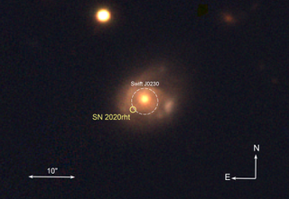 A blurry central circle shines orange/yellow amidst a cloudy haze. A white circle indicates the orb as black hole swj0230. Two additional orbs are in the upper portion of the photo.