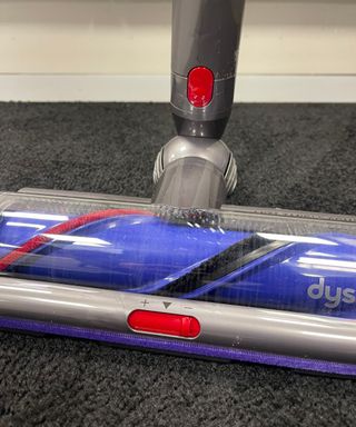 Close up of the Dyson V15 Detect's purple and gray Digital Motorbar floorhead on thick pile gray carpet in Future's test center