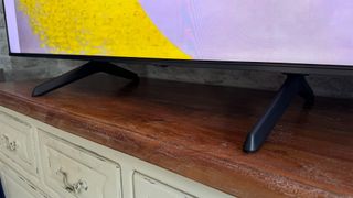 Hisense E7NQ Pro 75-inch 4K TV showing bottom of screen and feet on wooden dresser