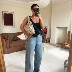 Emily Wells wearing a black tank top, beaded bag and blue jeans.