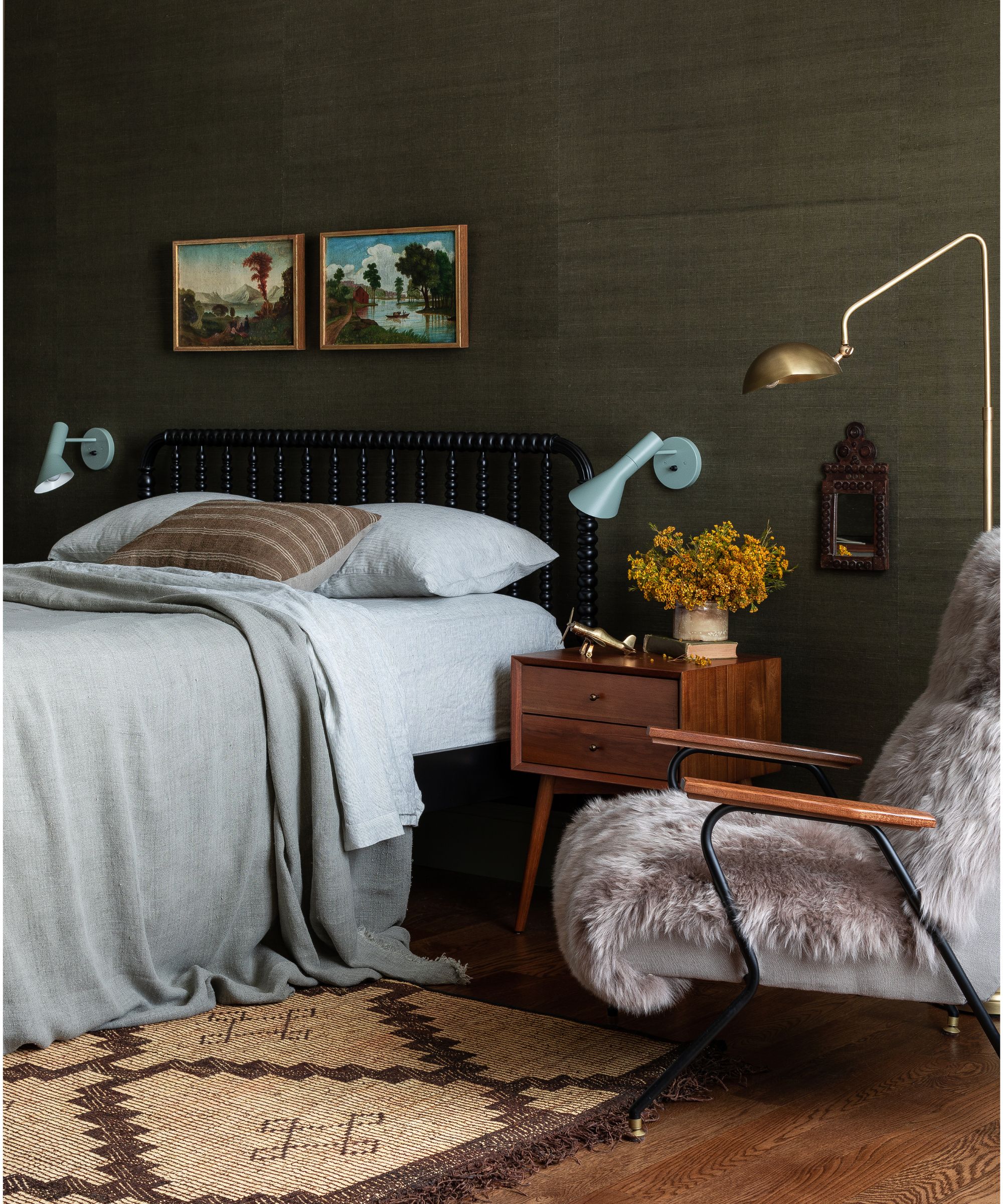Dark olive green bedroom by Heidi Caillier design with woven wallcovering, Midcentury bedside tables, armchair with sheepskin and light blue bedside wall lamps wall lamps