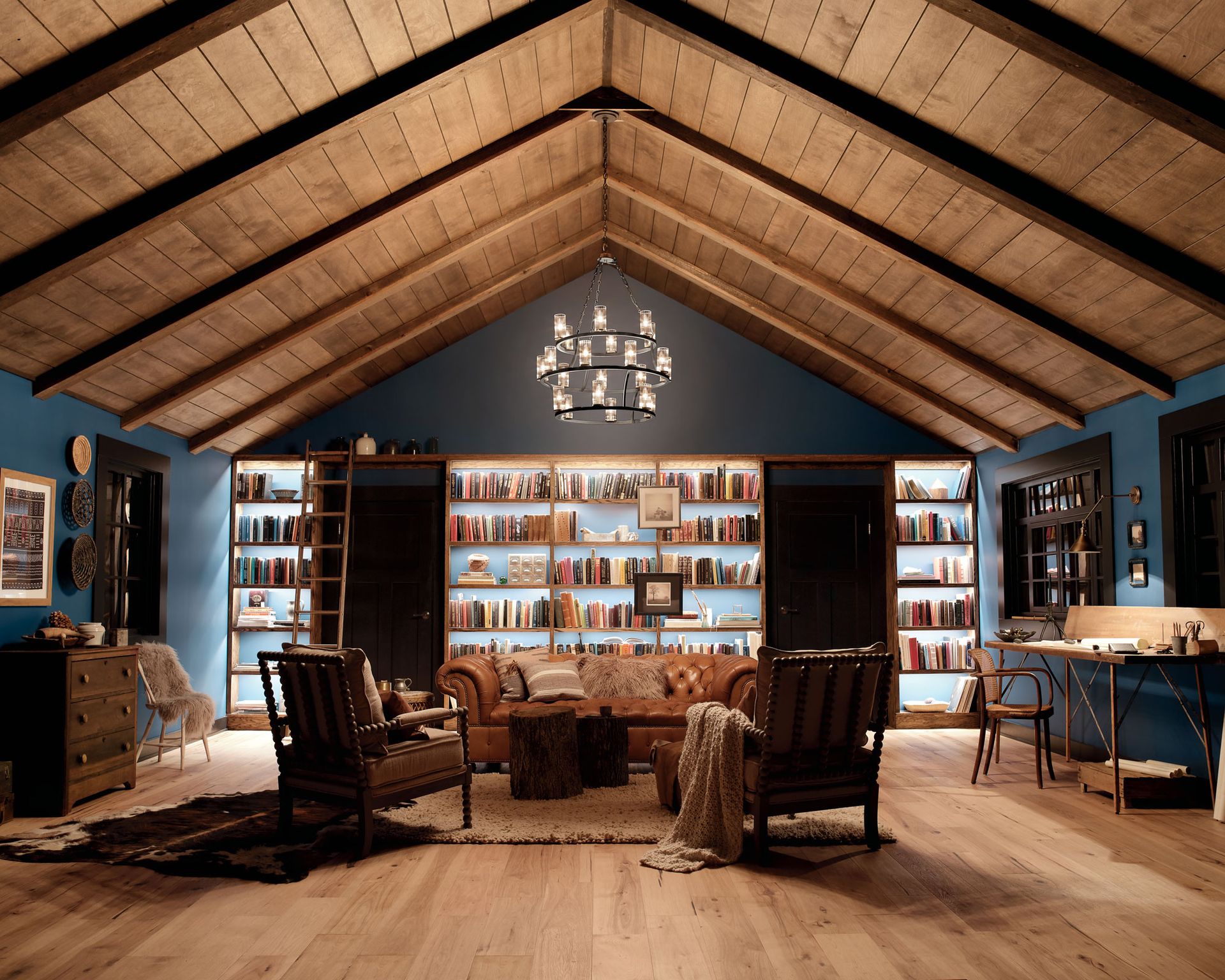 Kichler Lighting show how to plan living room lighting with ceiling and wall lighting in a large dark blue room with built in bookcases and leather chairs.