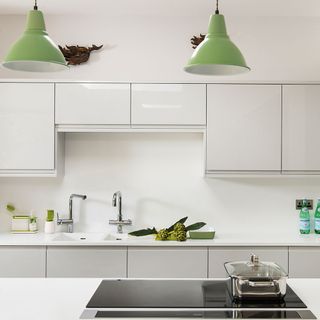 white countertop with white cabinet and green hanging lamp
