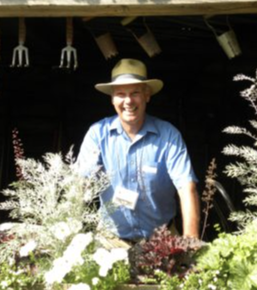 man in blue shirt wearing straw hat in a garden