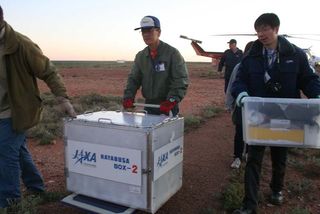 The sample return capsule (inside a box) from Japan's Hayabusa asteroid probe is transported by helicopter to the Instrumentation Building inside the Woomera Test Range after its June 13, 2010 landing. The re-entry capsule was housed in a temporary clean room before being returned to Japan on Tuesday.