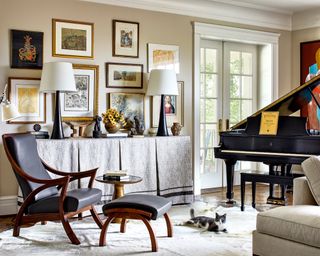 A living room with a black leather chaise lounge, a black grand piano and a gallery wall on neutral mottled wallpaper