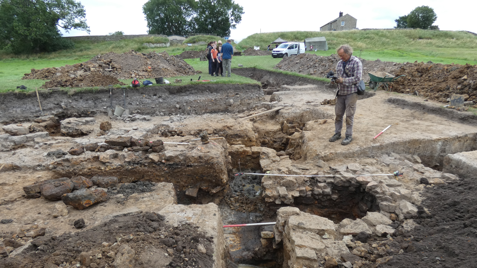 a light-skinned man looks out over a series of small excavated walls