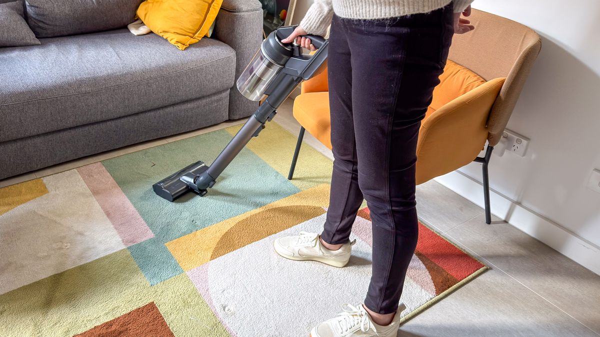 A person using the Samsung Jet 95S stick vacuum on a colourful rug