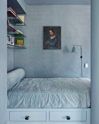 color drenched blue bedroom with built-in drawers, limewash walls, an artwork, wall light and display shelves