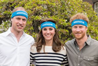 Prince William, Kate Middleton and Prince Harry standing together and wearing blue Heads Together sweatbands around their foreheads