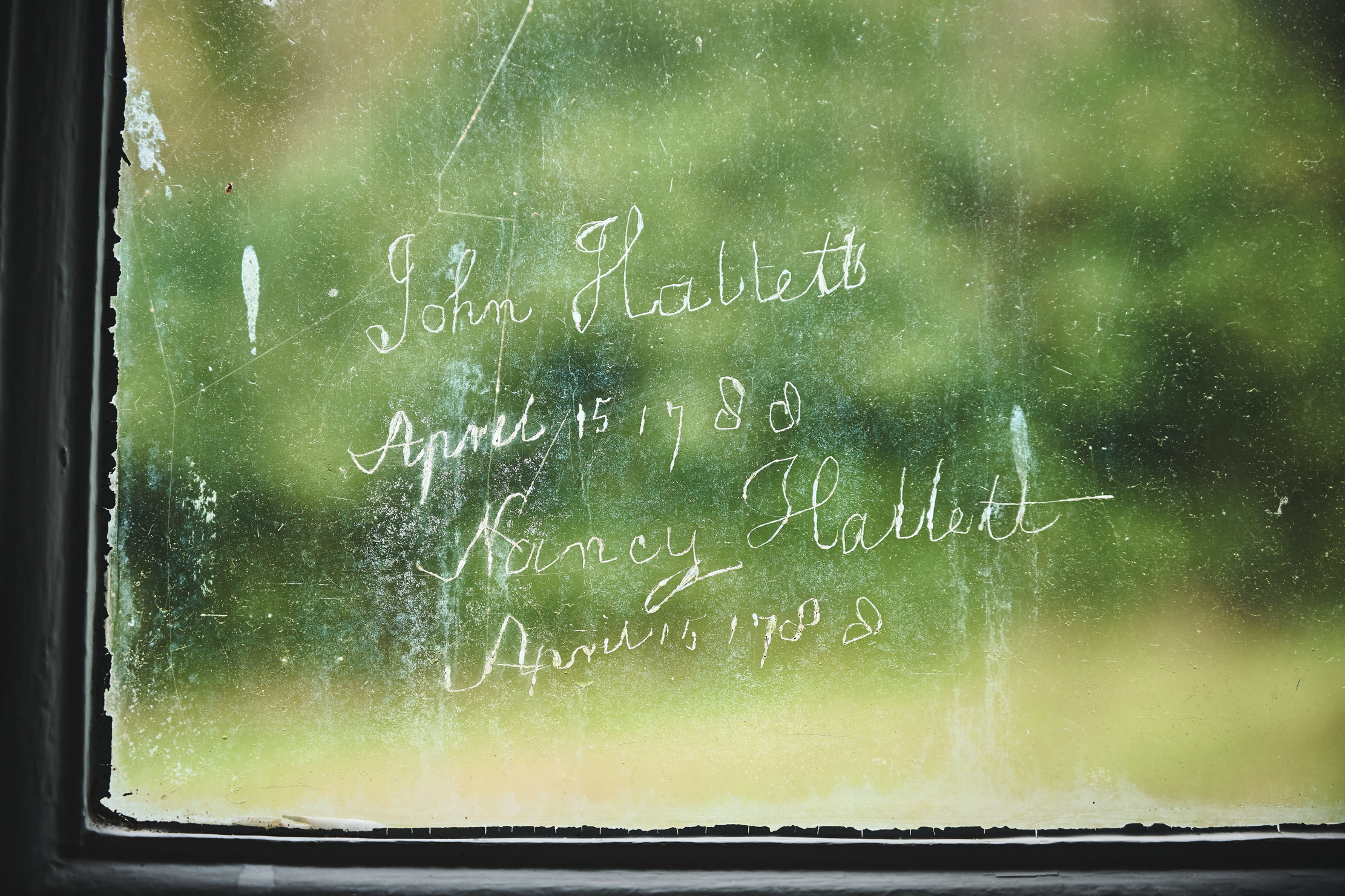 Grafitti on the window panes of Stedcombe House. The letters are faint scratches
