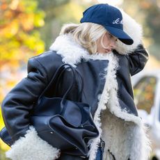 Elsa Hosk wearing a shearling coat, jeans, a baseball cap, The Row's Margaux bag, and a pair of Reebok Classic AZ sneakers.