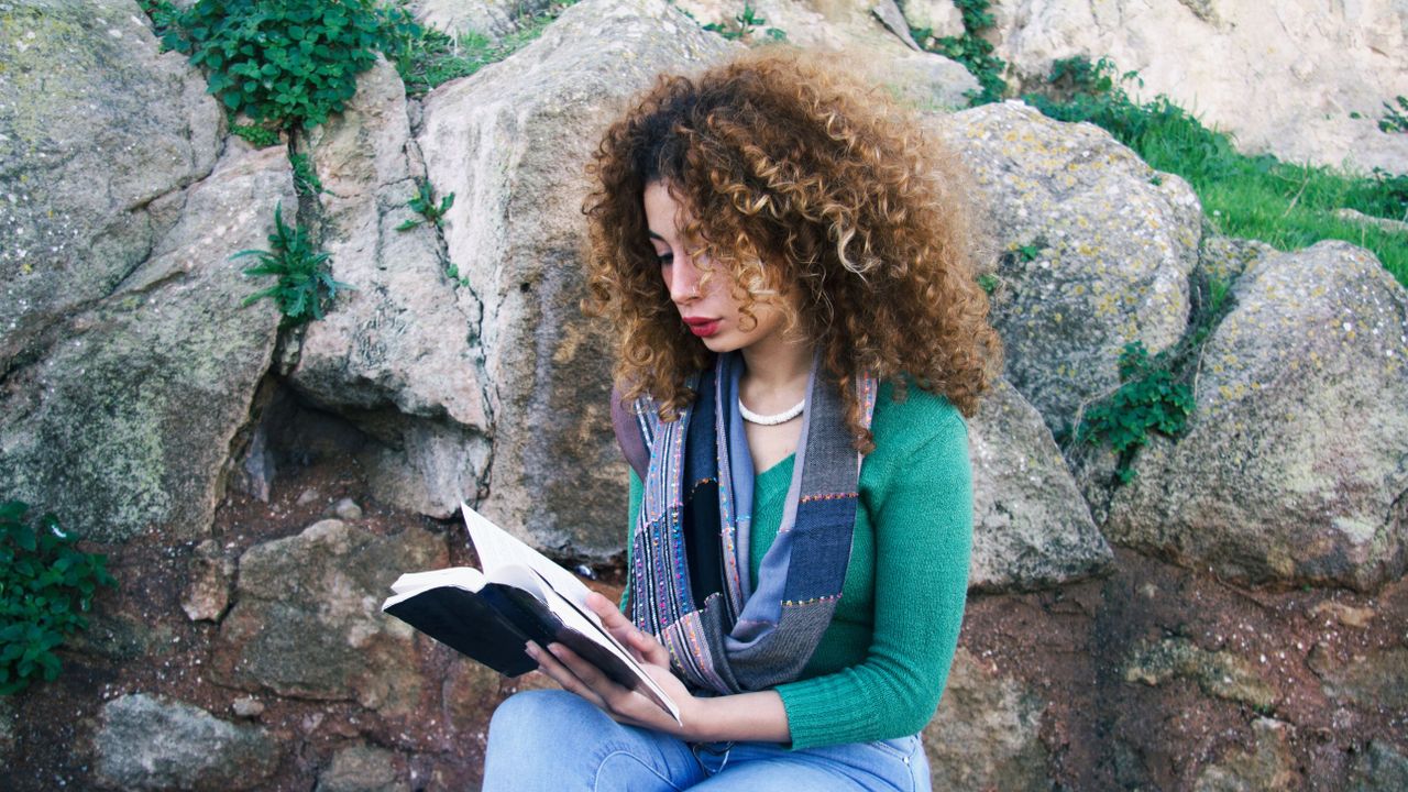 Human, Denim, Sitting, Rock, Ringlet, Street fashion, Reading, Bedrock, Jheri curl, Long hair, 