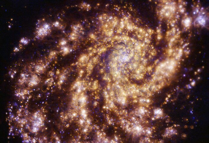 The bright spiral arms of NGC 4254 — a grand design spiral galaxy — wrap clearly around the galaxy&#039;s center. This new ESO image captures clouds of hydrogen, oxygen and sulfur gas shown in red, blue and orange respectively. The clouds of gas are ionized by newly formed stars.