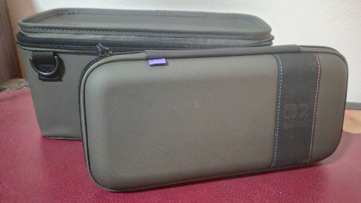 Photo of the top of a large Switch 2 case sitting on a red box, with the main body of the base behind it.