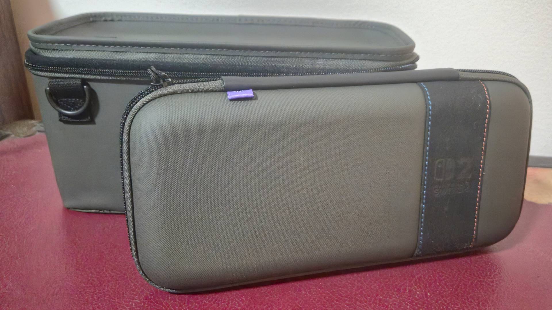 Photo of the top of a large Switch 2 case sitting on a red box, with the main body of the base behind it.