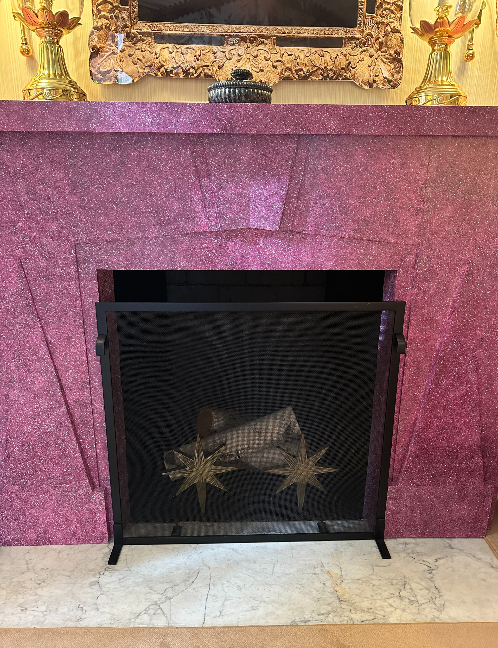 Pink fireplace area featuring starburst andirons