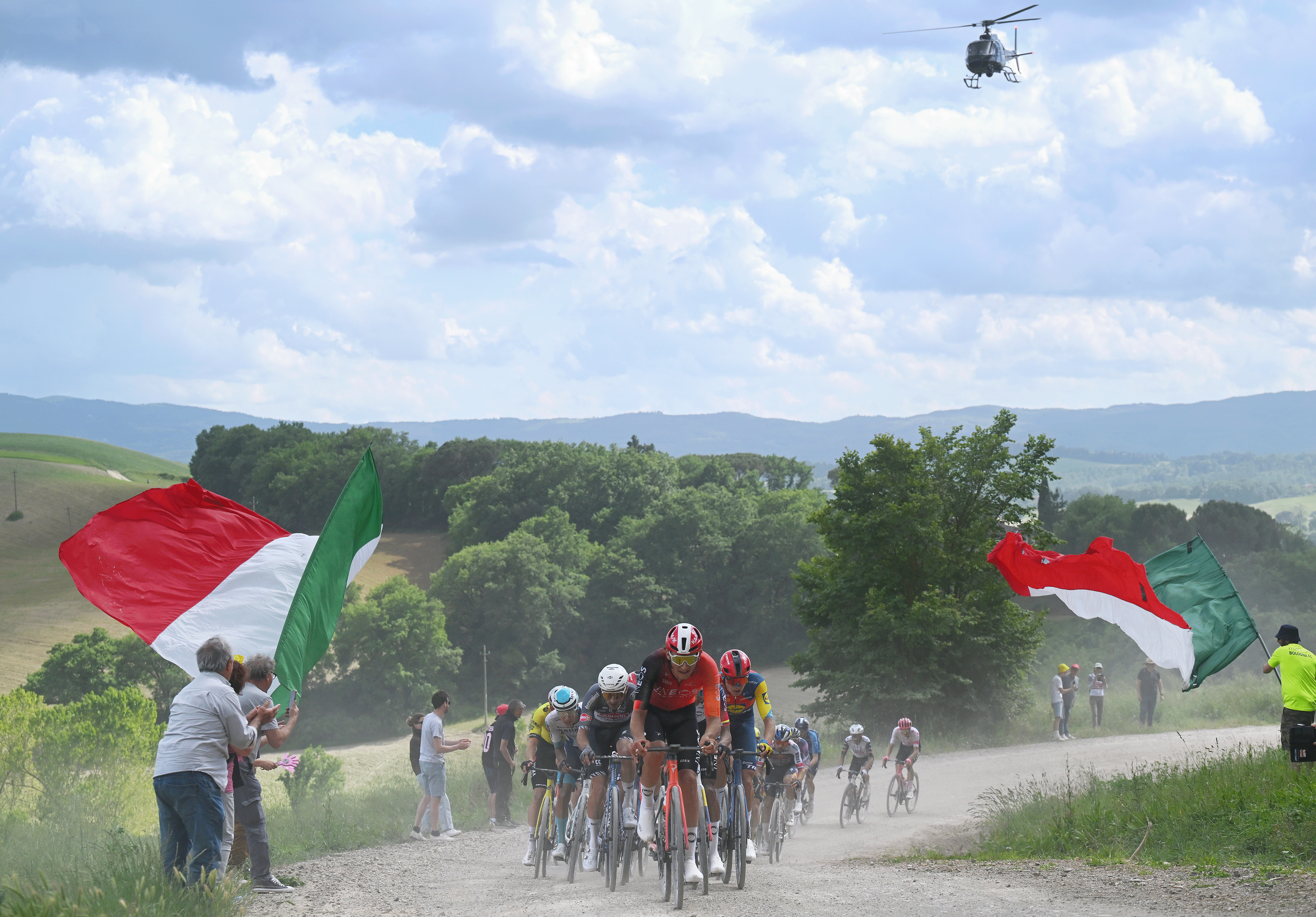 Josh Tarling leads the peloton through two Italian flags